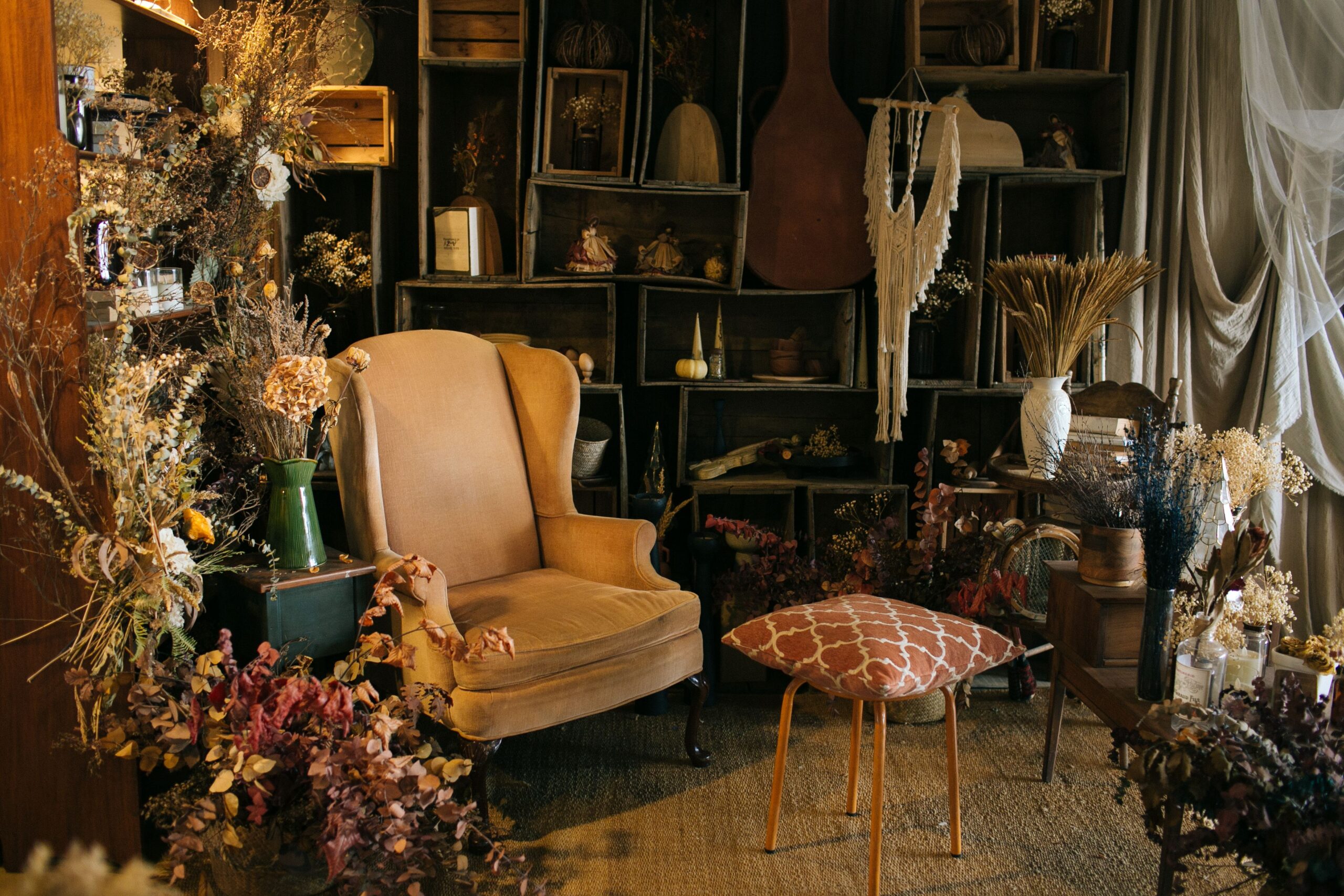 Boho room vignette with handmade objects, vintage lamp, candles, dried branches, ceramic vase and warm layered lighting