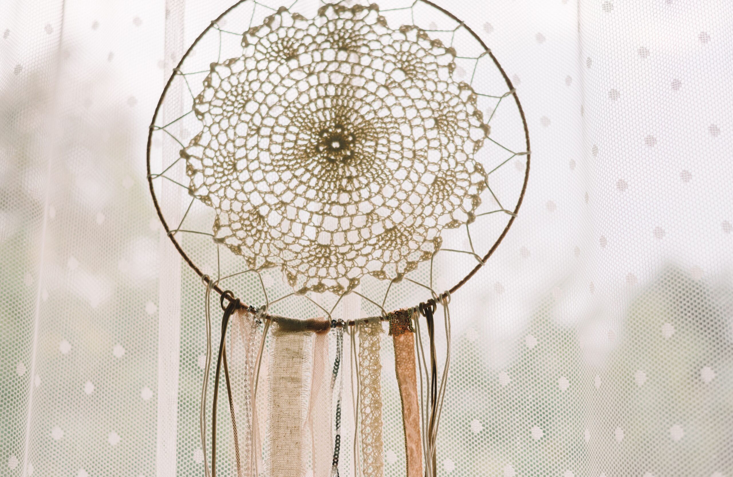 A boho bedroom with layered rugs, soft bedding, patterned cushions, and a chunky throw.
