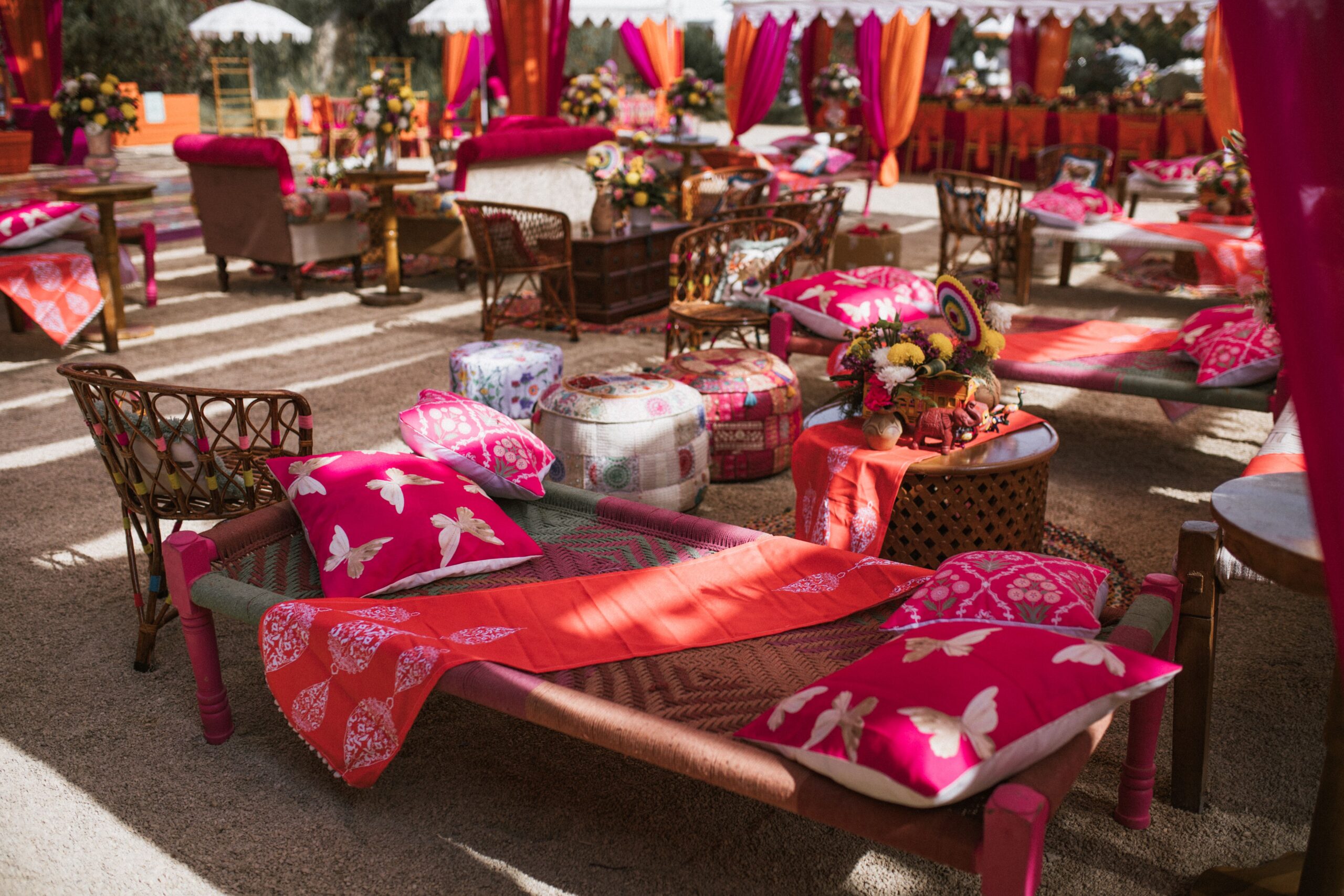 A boho seating area with varied wood, rattan, cane, and low-profile furniture around a rug.