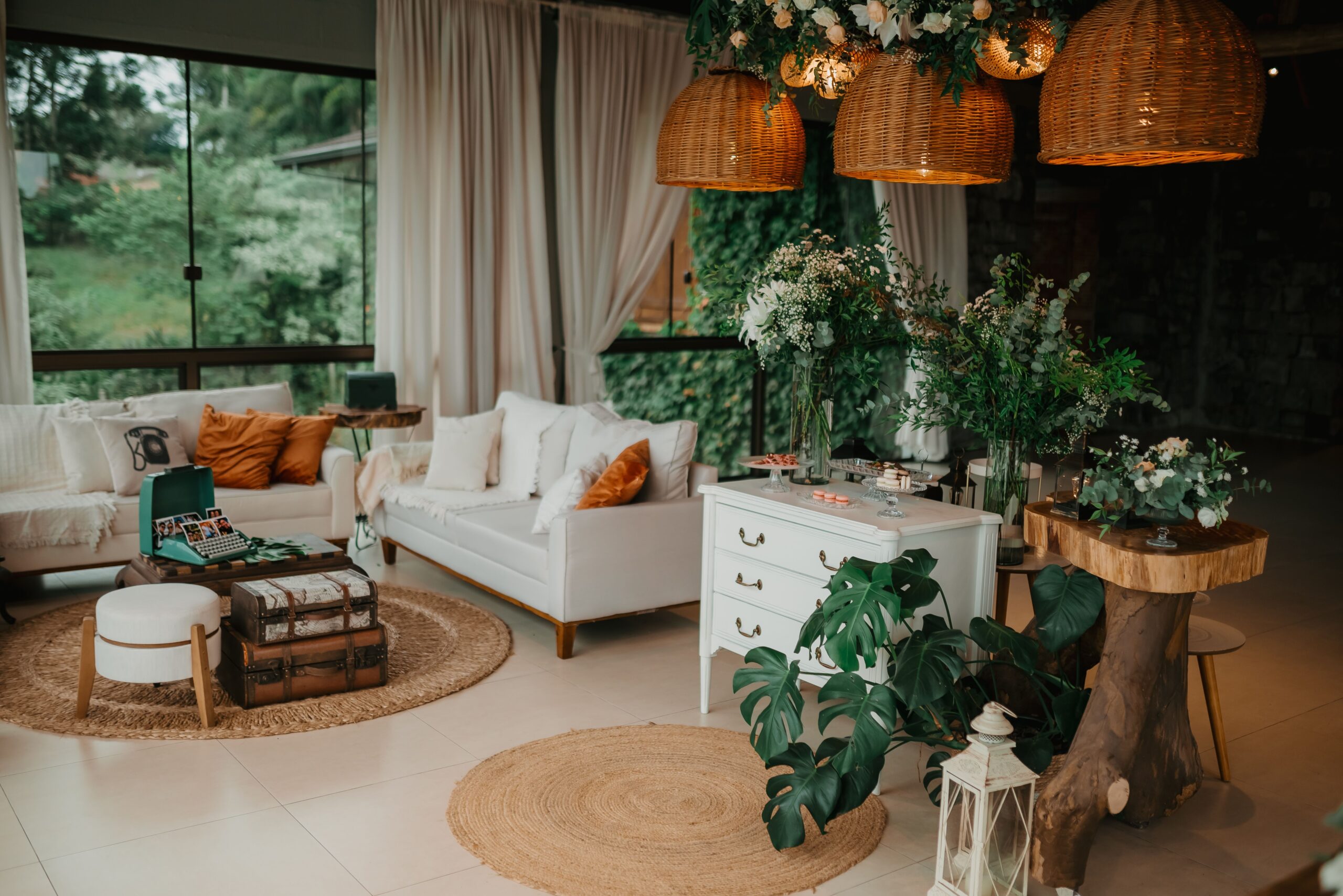 Low-profile boho seating arrangement with a sofa, cane chair, round wood table, rug, and woven ottoman.